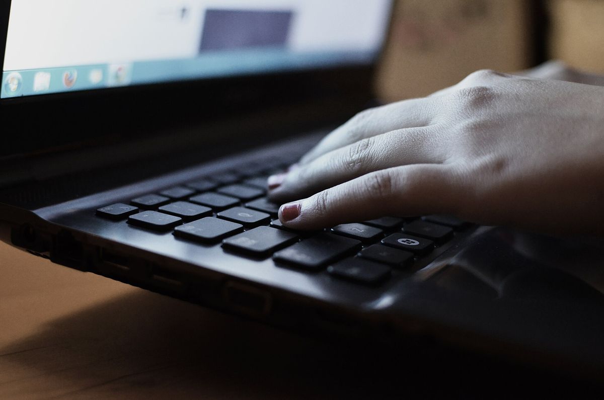 Hands typing on a laptop keyboard on a desk.